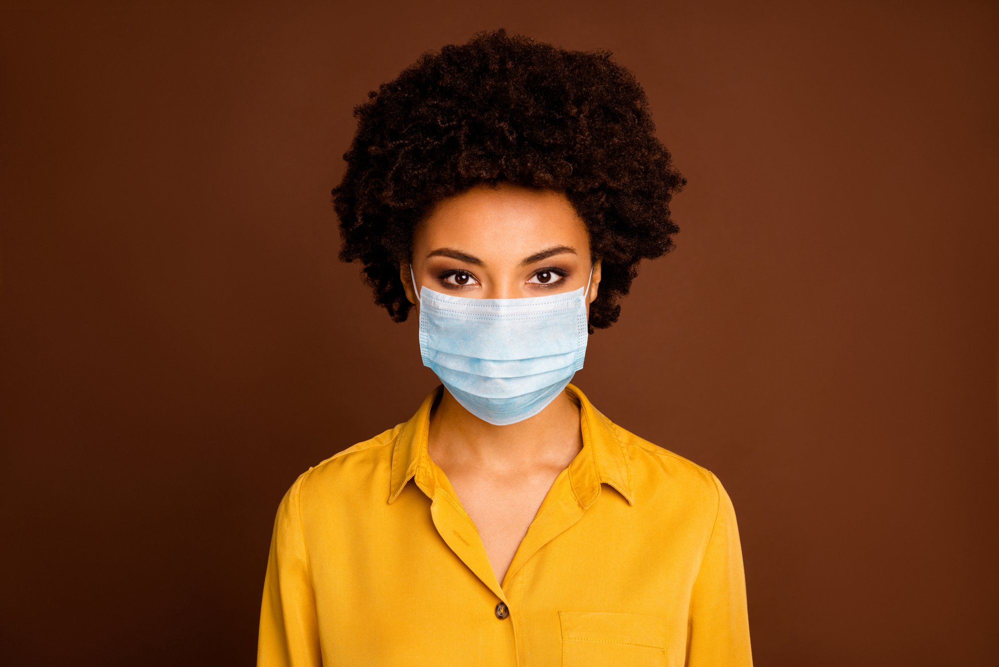 Close-up portrait of pretty dark skin wavy-haired lady in yellow shirt gauze mask concept sickness illness disease life sars cov ncov prevention isolated